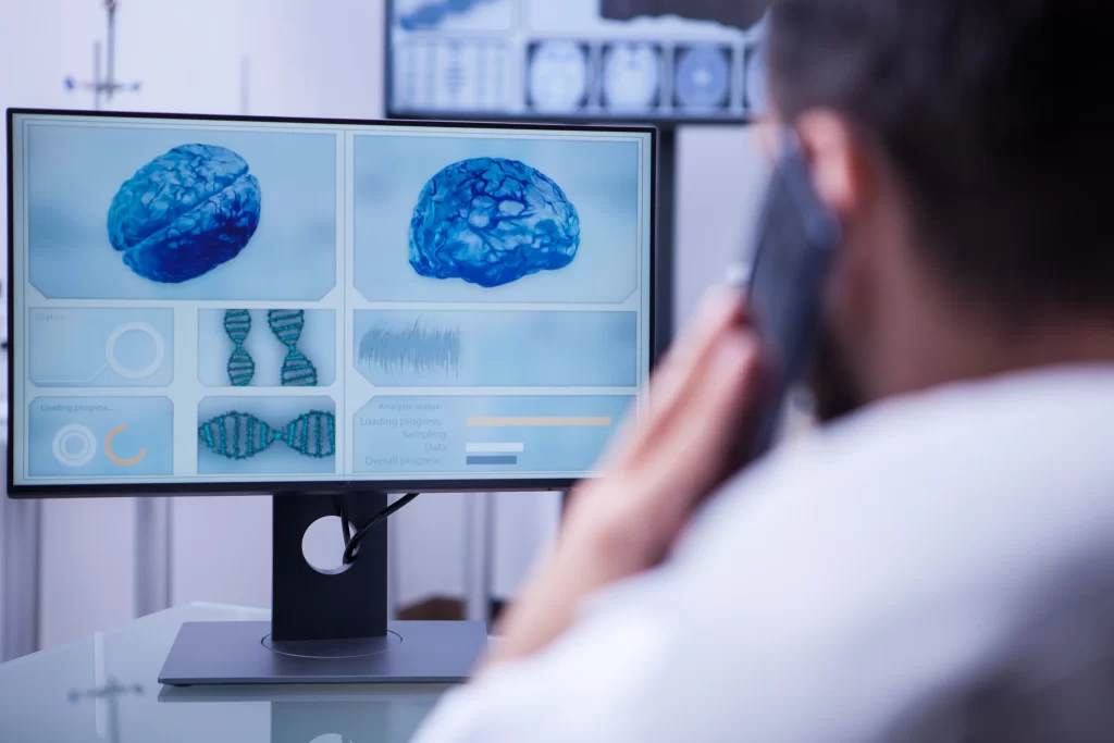 Médico observando imágenes cerebrales y secuencias genéticas en una pantalla digital, ilustrando el uso de IA en la gestión oncológica.