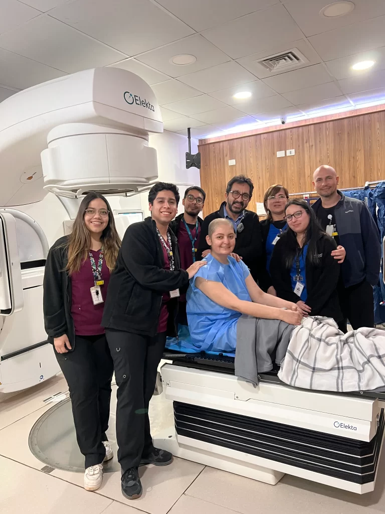Equipo médico de ROS Clínica Oncológica en Concepción acompañando a una paciente durante su tratamiento de radioterapia con tecnología Elekta. Fotografía tomada en la sala de tratamiento oncológico.