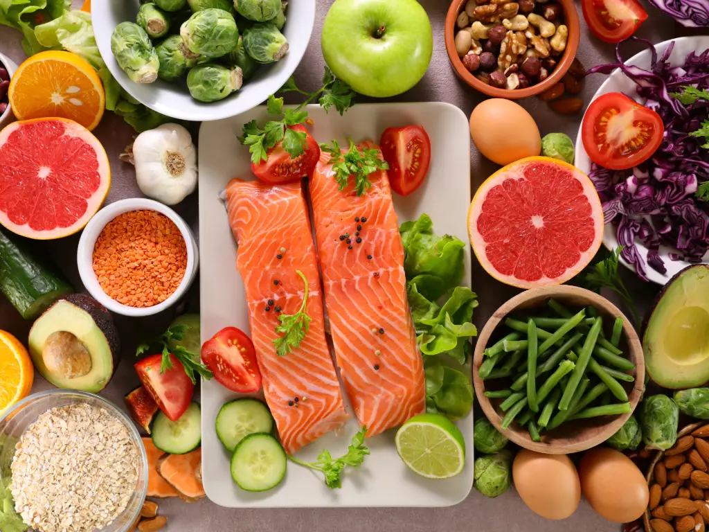 Selección de alimentos nutritivos como salmón, verduras, frutas y frutos secos utilizados en planes de nutrición oncológica.