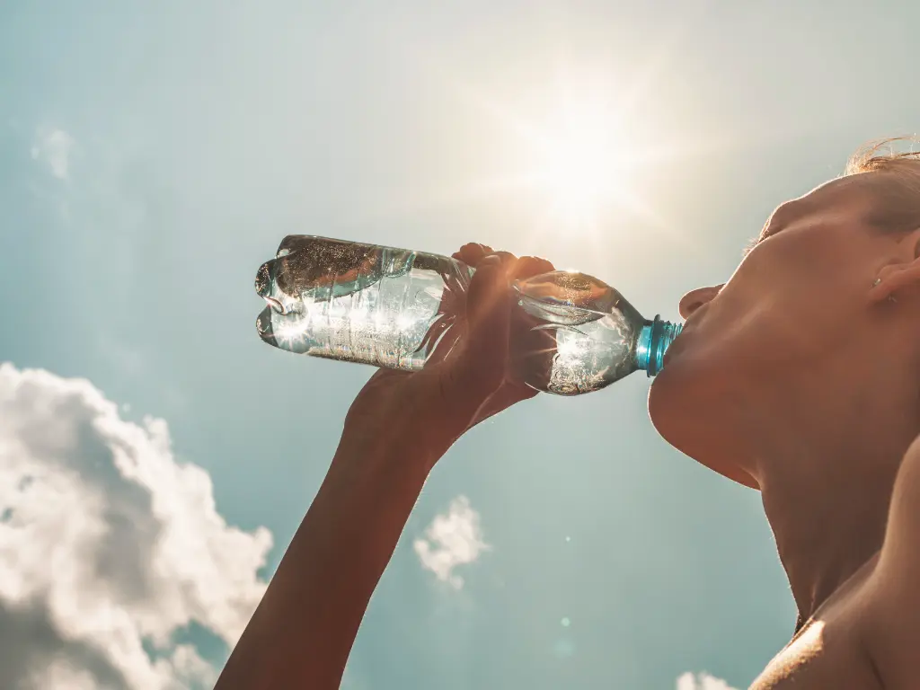Persona hidratándose durante altas temperaturas en contexto de emergencias ambientales