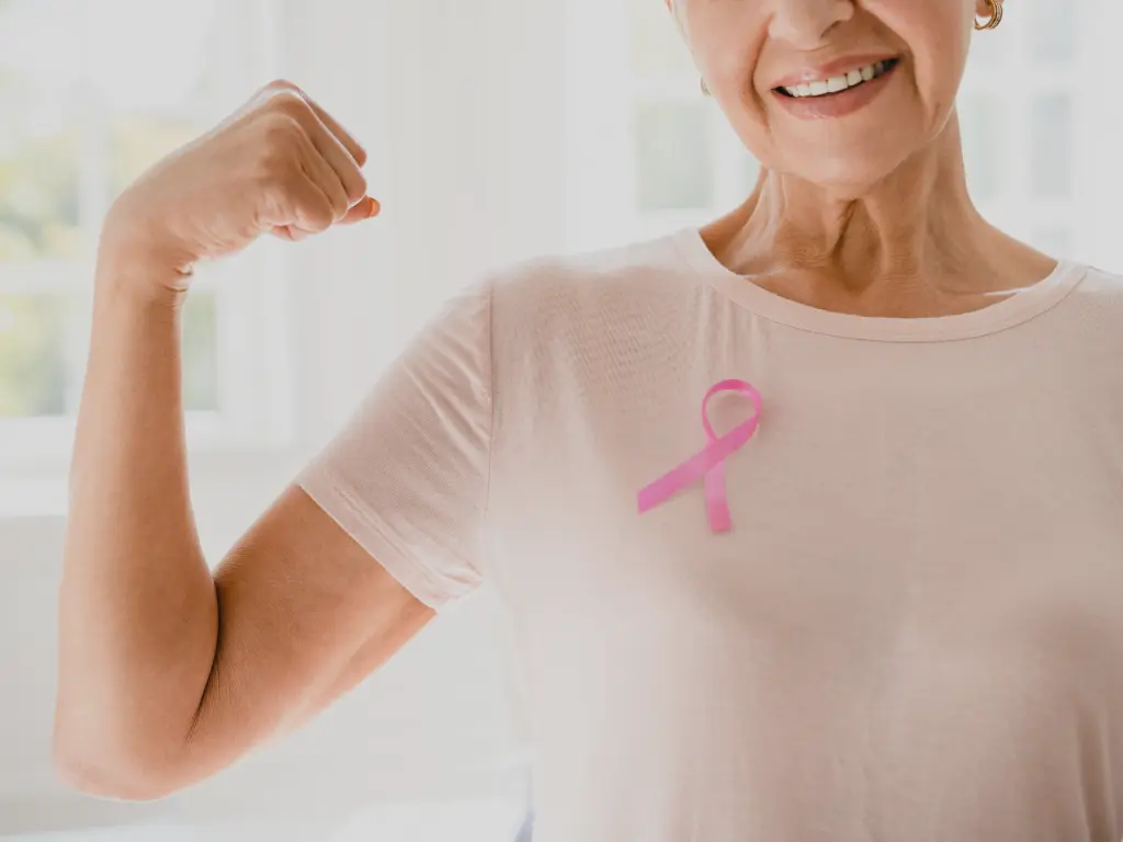 Mujer mostrando fortaleza con una cinta rosada en el pecho durante el Día Mundial contra el Cáncer, símbolo de concientización y prevención.
